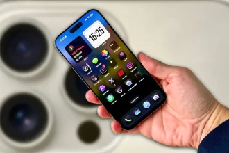 A sleek iPhone 16 Pro Max in Titanium with a polished titanium frame, showcasing its large 6.9-inch Super Retina XDR OLED display. The screen features a Dynamic Island cutout at the top, and the triple-lens rear camera system includes an upgraded 48MP main sensor, ultra-wide lens, and telephoto lens with enhanced low-light capabilities. The device is shown resting on a minimalist surface, screen displaying a vivid nature scene to highlight its vibrant colors and sharp resolution.