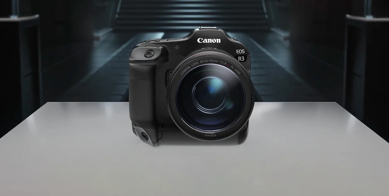 A professional Canon EOS R3 mirrorless camera with a sleek black magnesium alloy body, featuring a deep grip, a high-resolution electronic viewfinder (EVF), and a vari-angle touchscreen LCD. The camera is shown with an RF-mount lens attached, showcasing its rugged, weather-sealed design ideal for sports and action photography